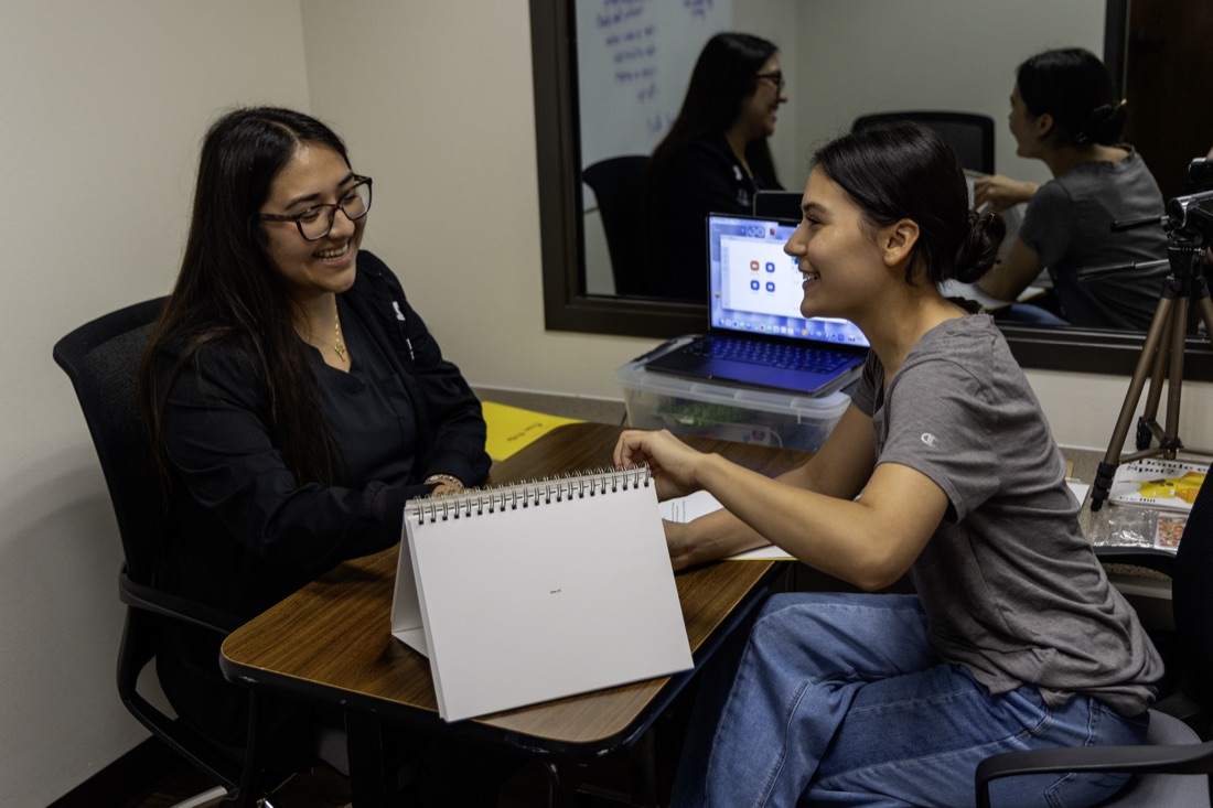 Two adults practice an assessment with tabletop materials