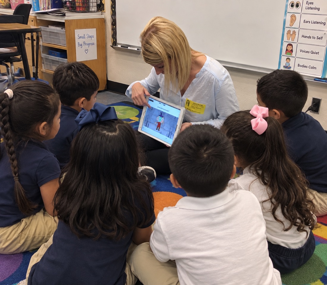 An adult guides children with a tablet in a classroom